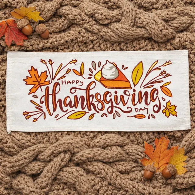 Thanksgiving-themed towel with pie illustration on a knitted surface