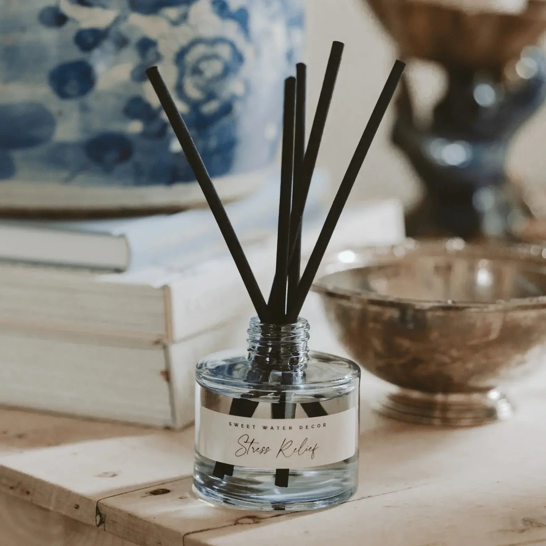 Stress Relief reed diffuser in clear glass jar with black reeds, cozy farmhouse decor on wooden shelf