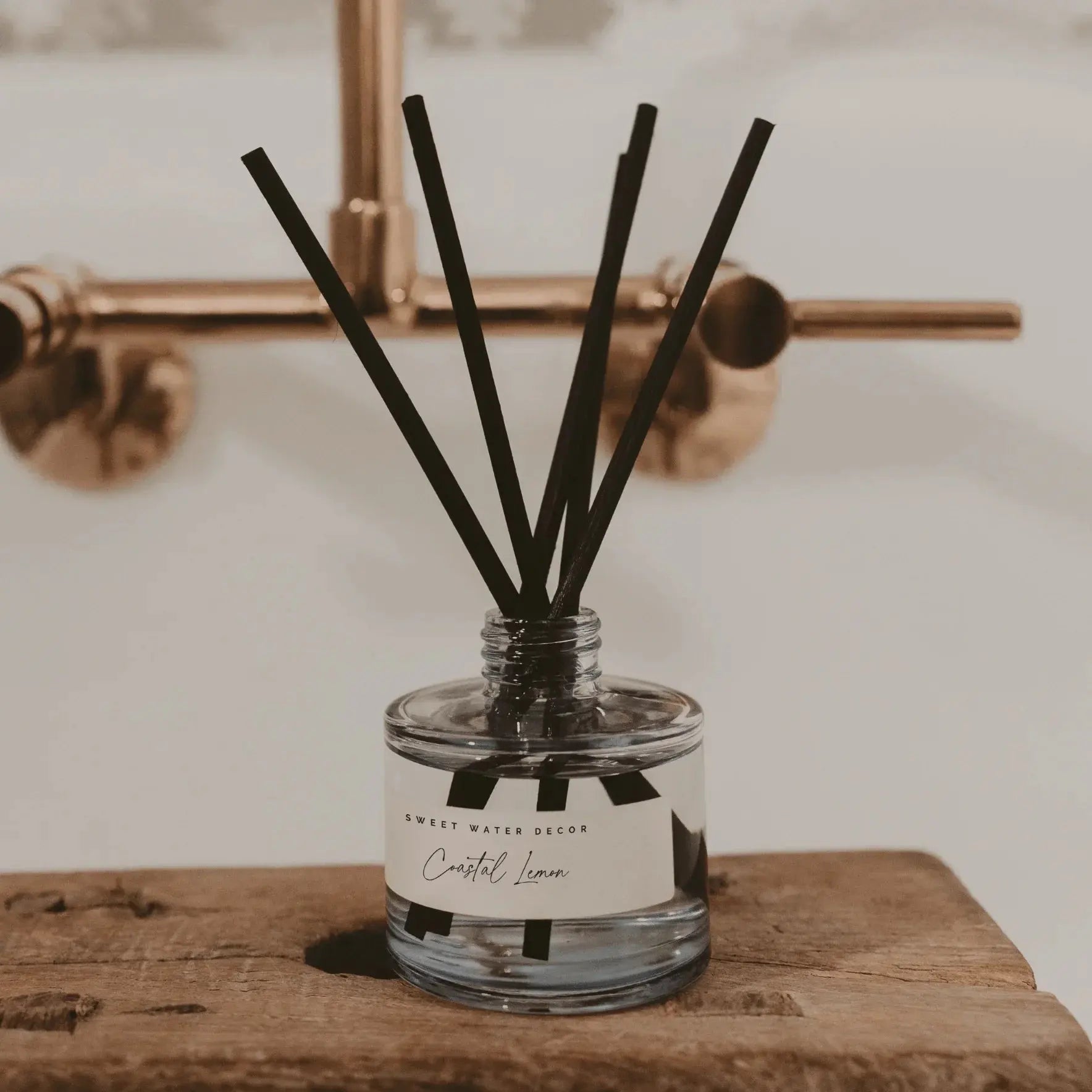 Coastal Lemon reed diffuser on rustic wood, farmhouse bathroom decor with gold fixtures