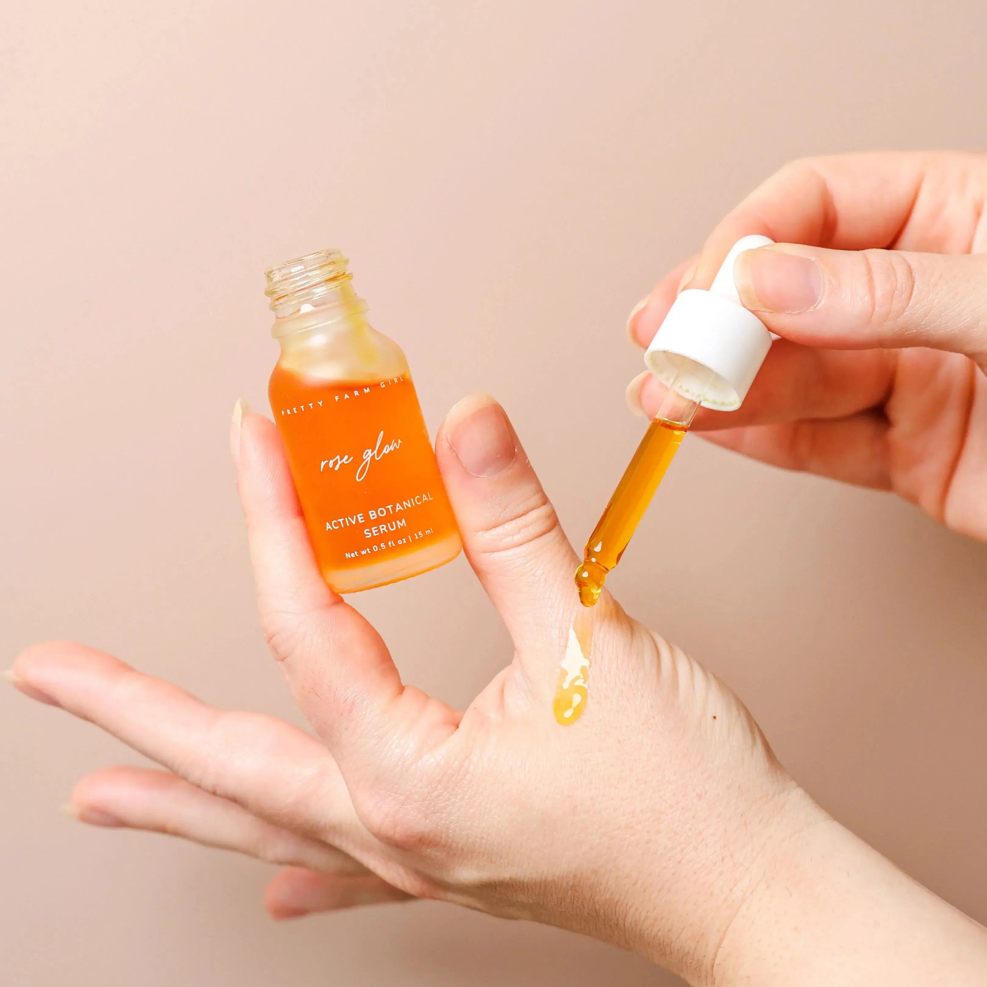 Rose Glow Active Botanical Serum being applied to hand, golden oil dropper, natural skincare