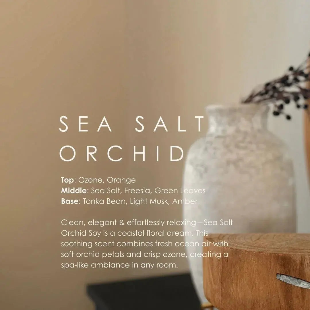 Sea Salt Orchid soy candle with coastal floral scent, displayed beside rustic vase and wooden stool for cozy home decor