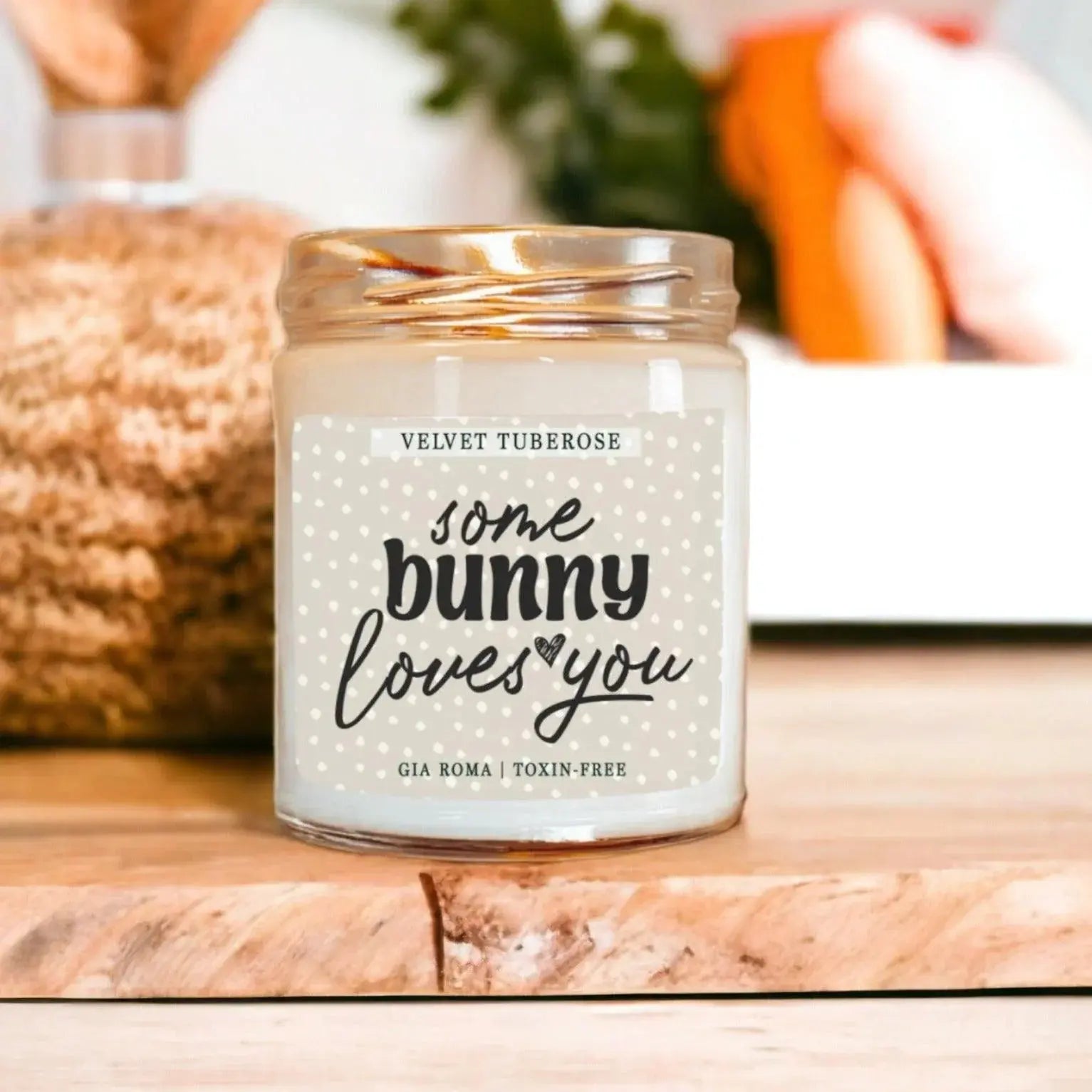 Candle jar labeled 'some bunny loves you' on a wooden surface with blurred background