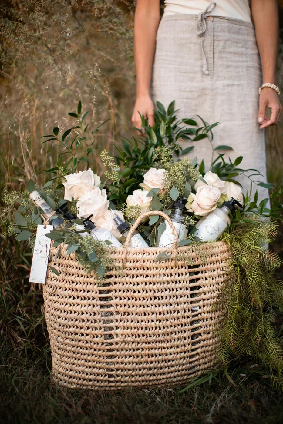 Woven basket with bath essentials, soft roses, and greenery for cozy farmhouse decor