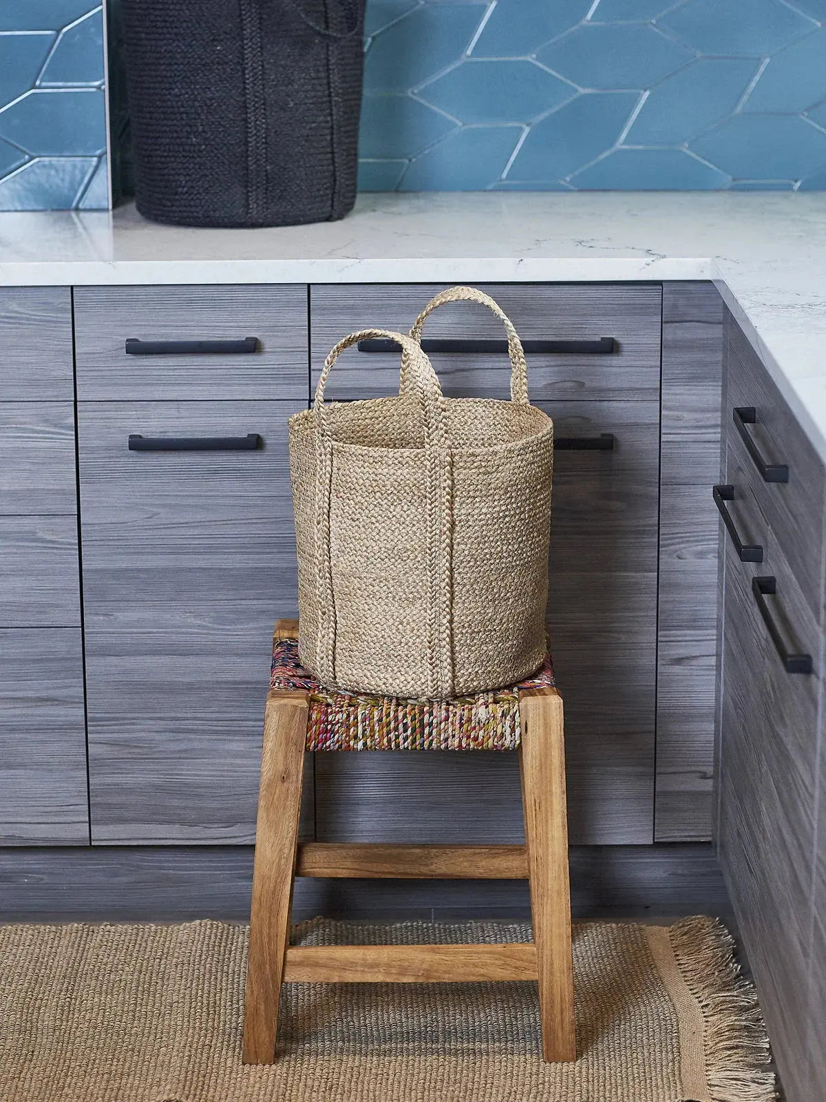 Natural woven seagrass basket with handles on wooden stool in modern farmhouse kitchen