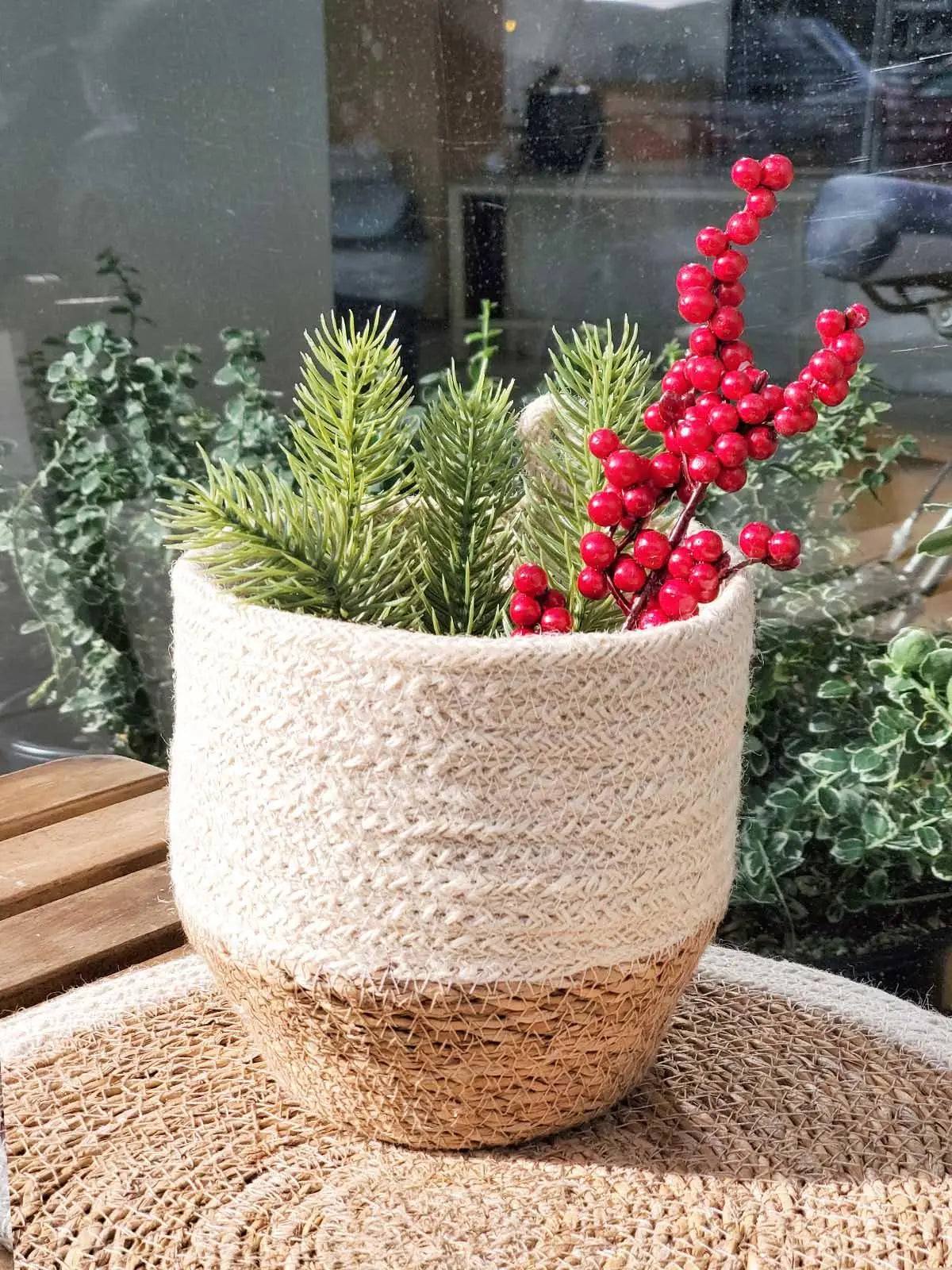 Cozy farmhouse-style woven basket with faux pine and red berries, perfect for holiday home decor