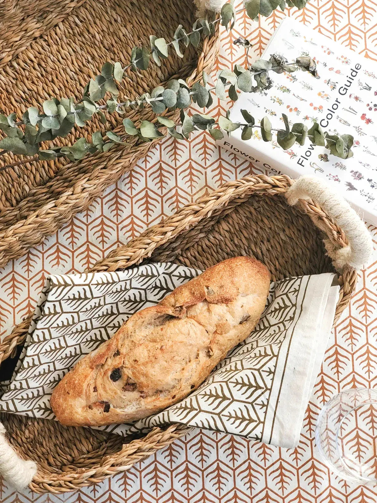 Cozy farmhouse-style wicker tray with rustic bread, eucalyptus, and patterned napkin for cottage decor