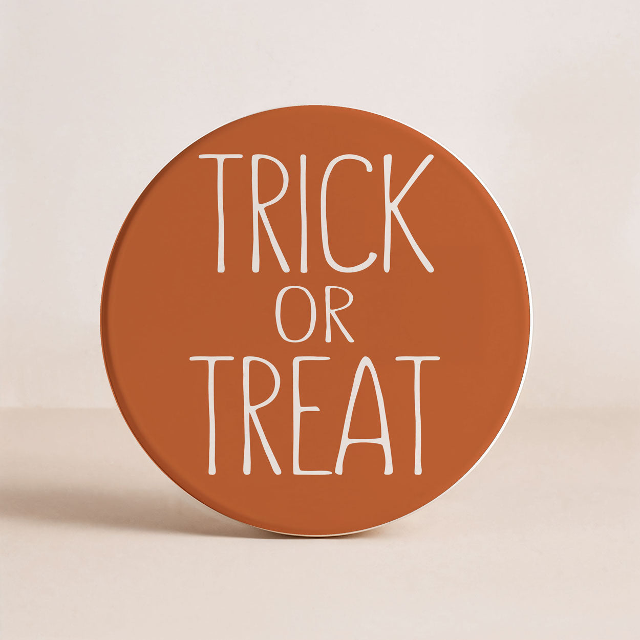 Round brown sign with 'TRICK OR TREAT' text on a beige background