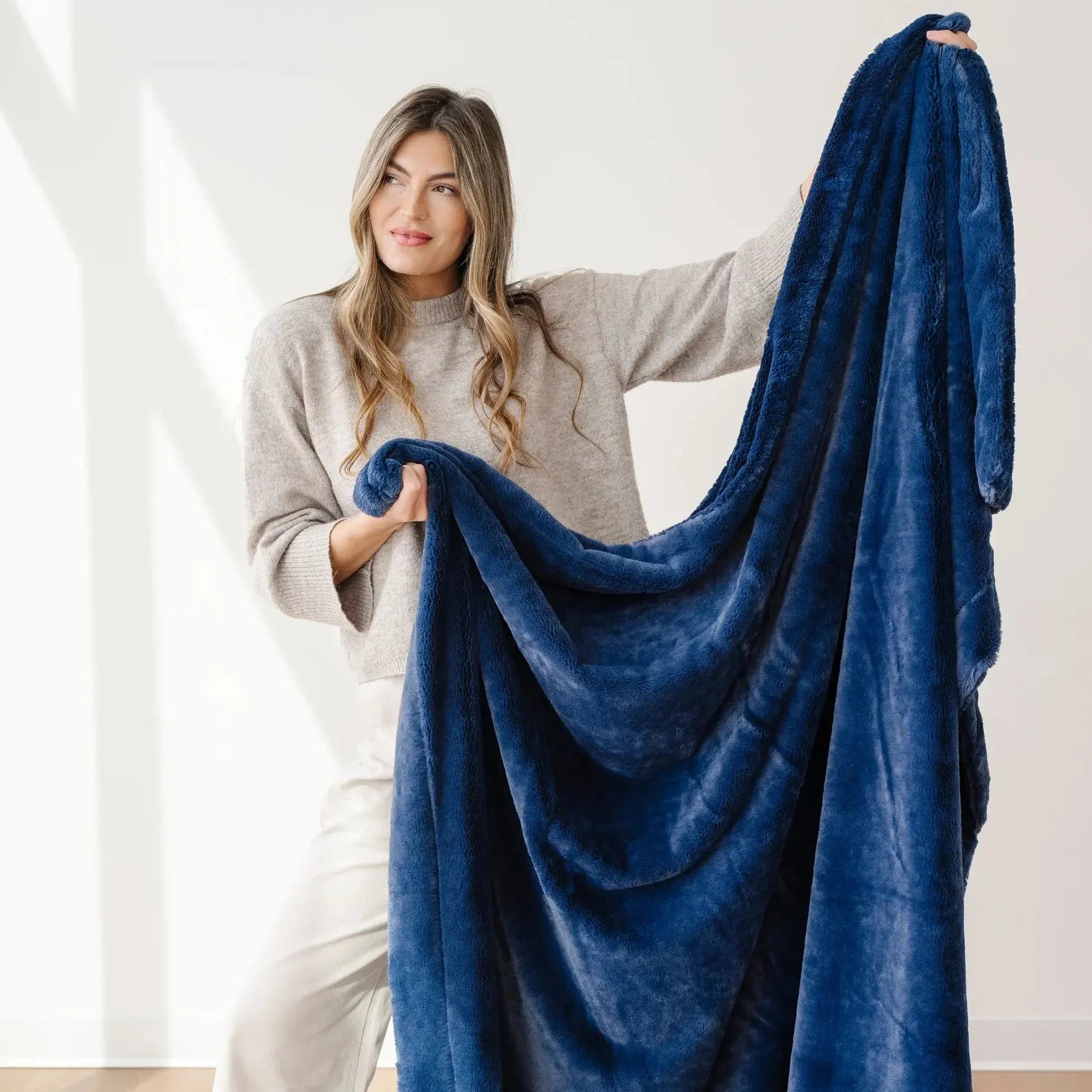 Woman holding a blue blanket in a bright room
