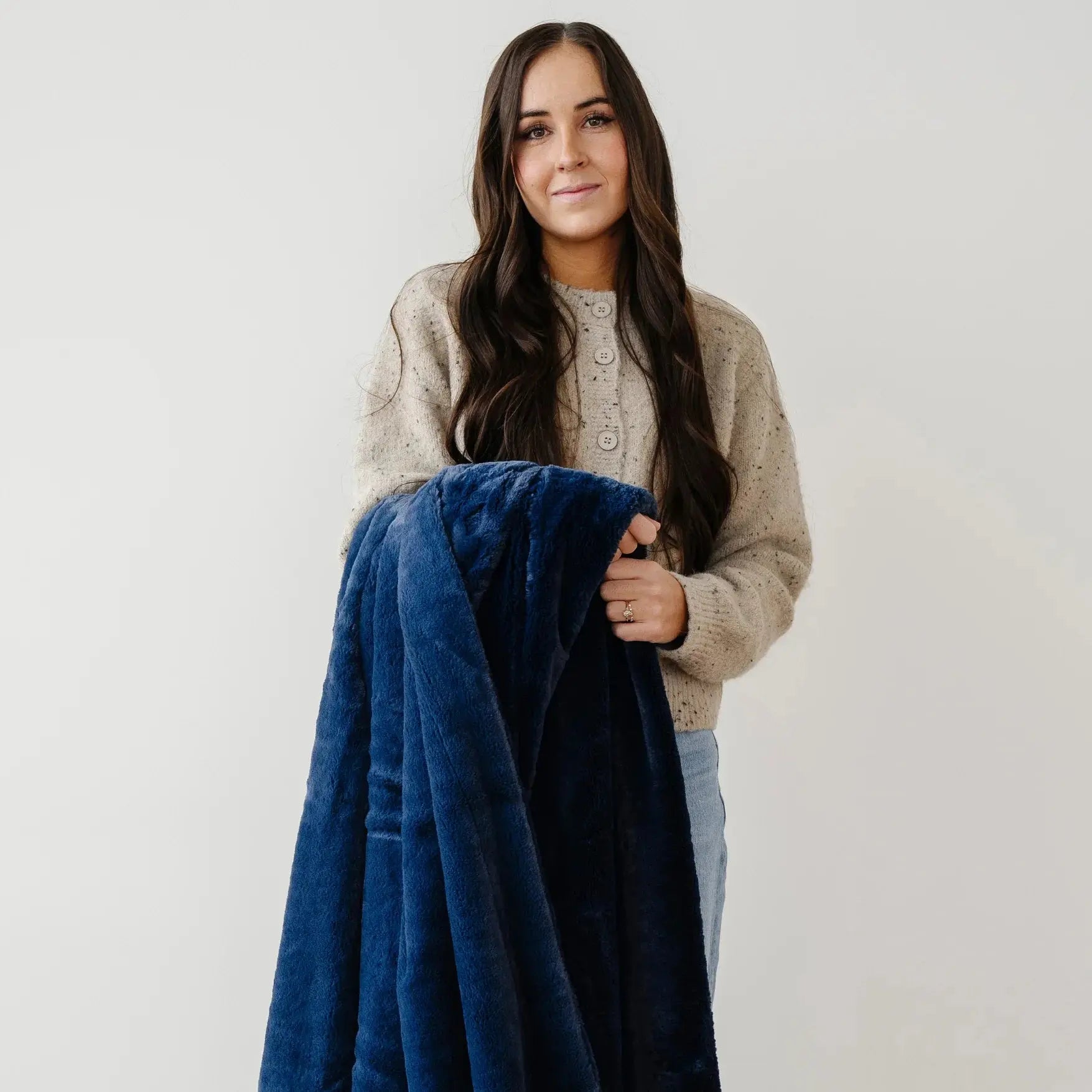 Woman holding a blue blanket against a plain background
