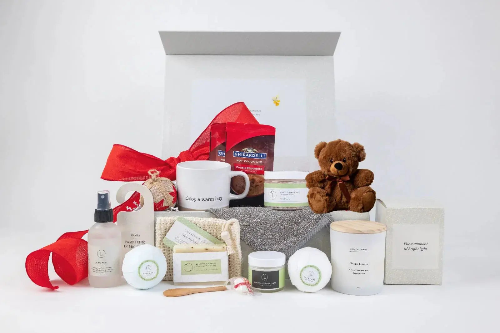 Cozy gift box with teddy bear, scented candle, bath products, hot cocoa, and mug for relaxation and self-care