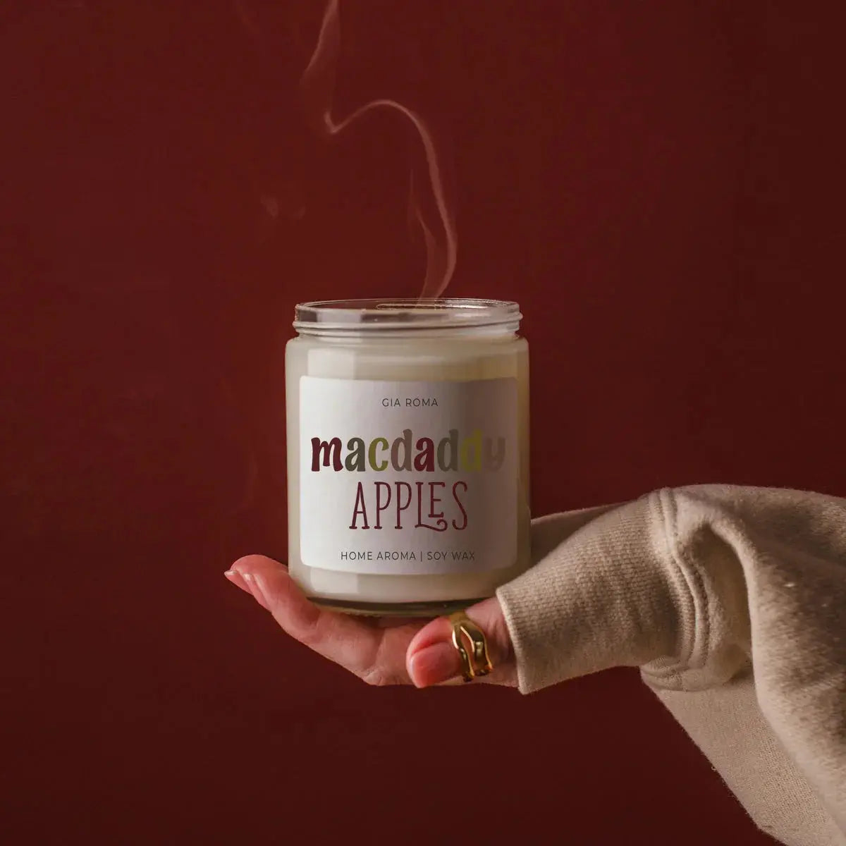 Hand holding a 'comfy & cozy' candle against a dark background