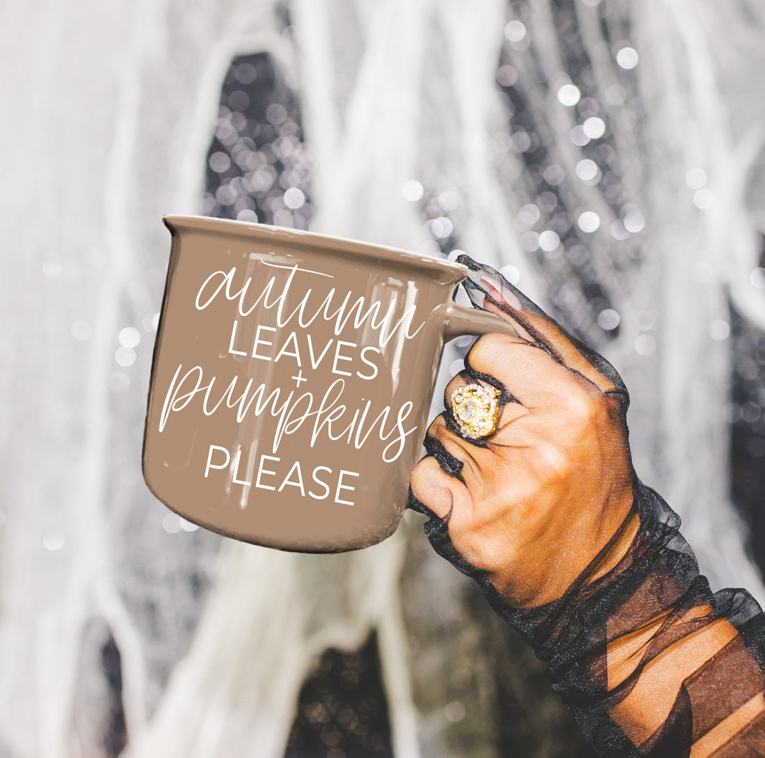 Hand holding a mug with 'Autumn leaves + pumpkins please' text against a snowy background