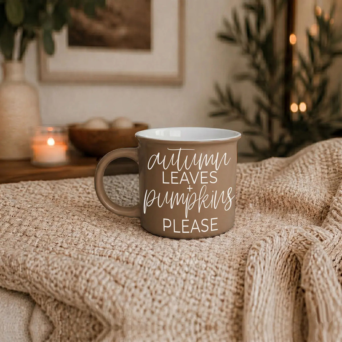 Mug with 'hello fall' text on a textured surface with cozy decor
