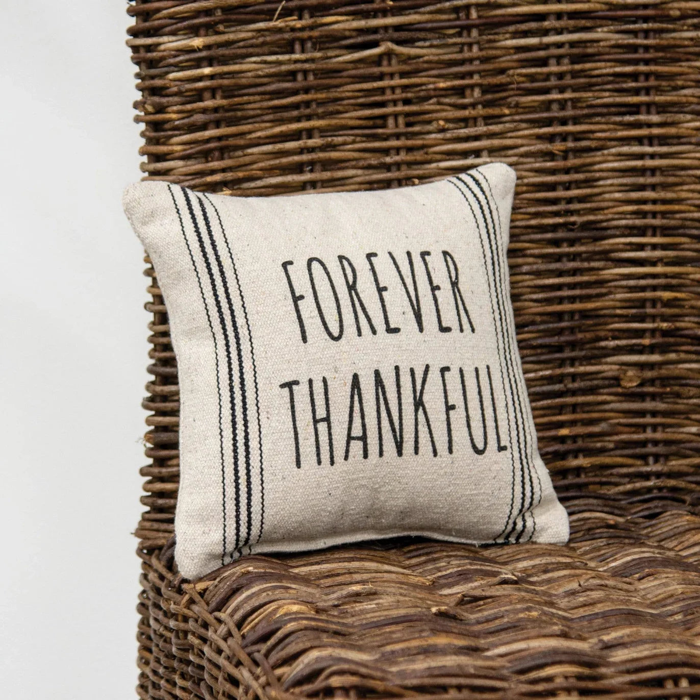 Pillow with 'Forever Thankful' text on a wicker chair