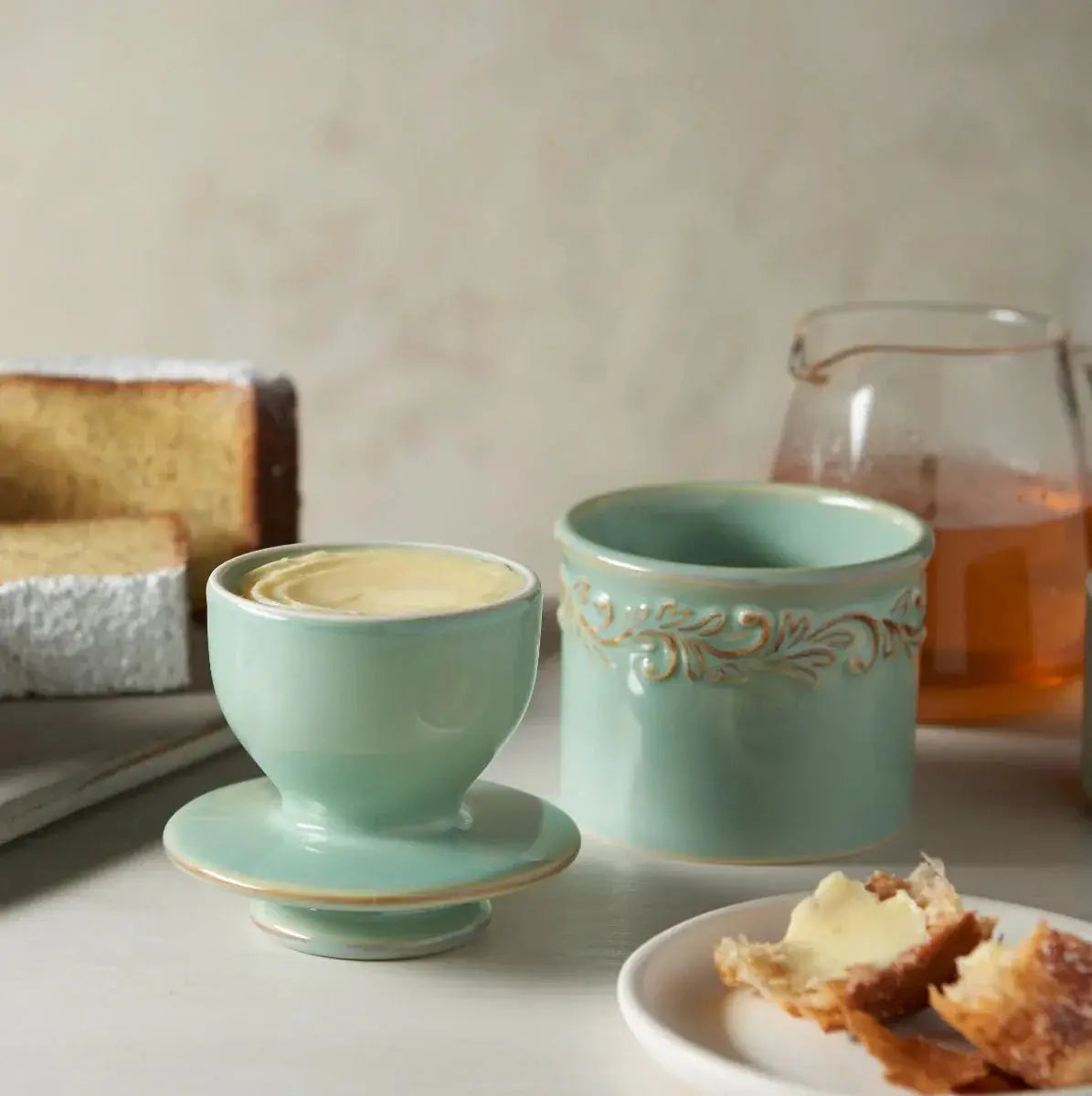 Mint green ceramic egg cup with saucer, matching ramekin, and buttered bread for cozy farmhouse breakfast