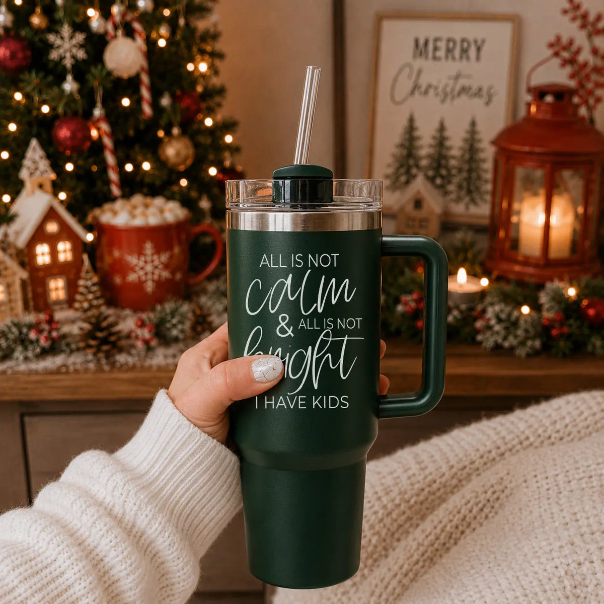 Person holding a tumbler with a humorous Christmas quote in front of a decorated Christmas tree.