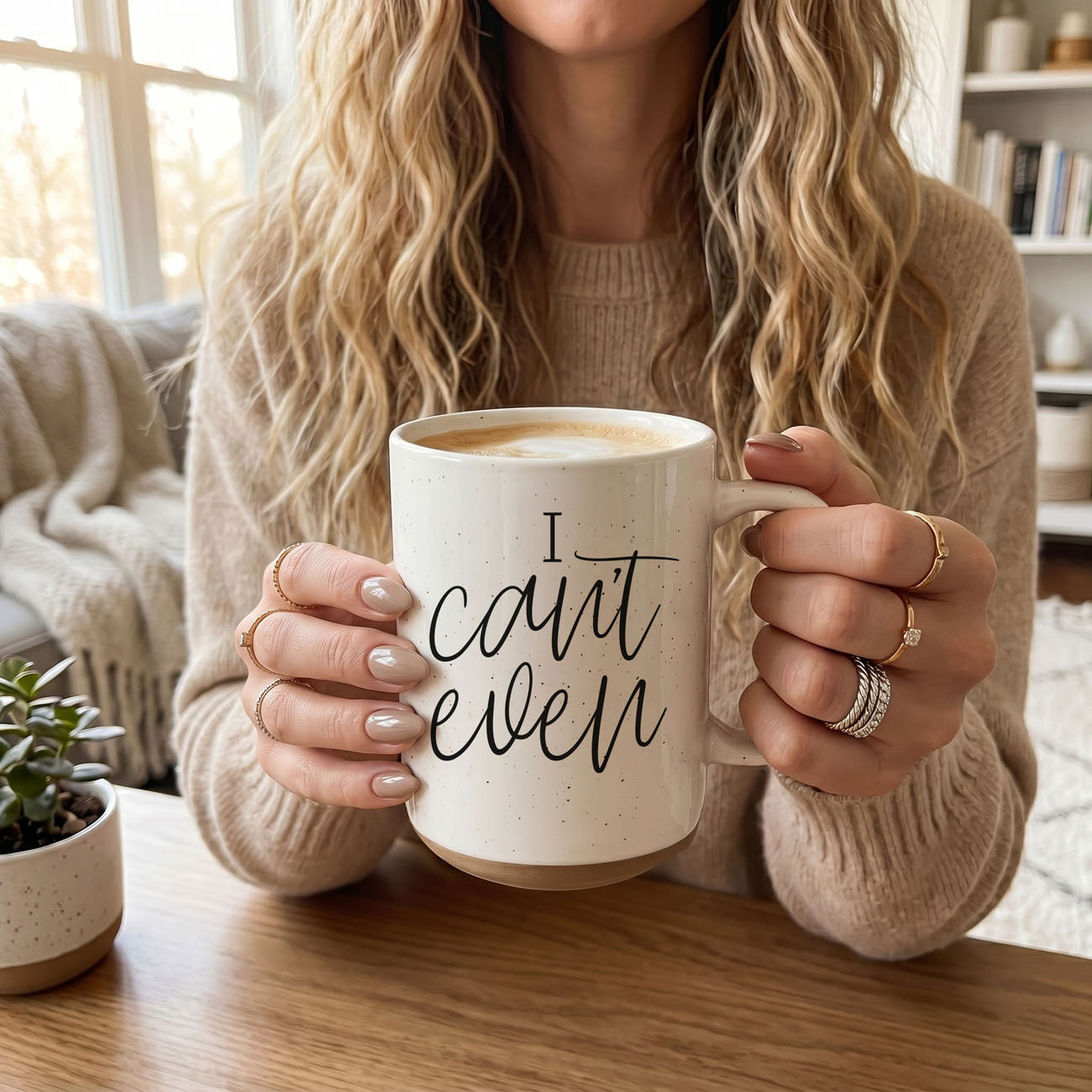 Person holding a mug with 'I can't even' text in a cozy indoor setting