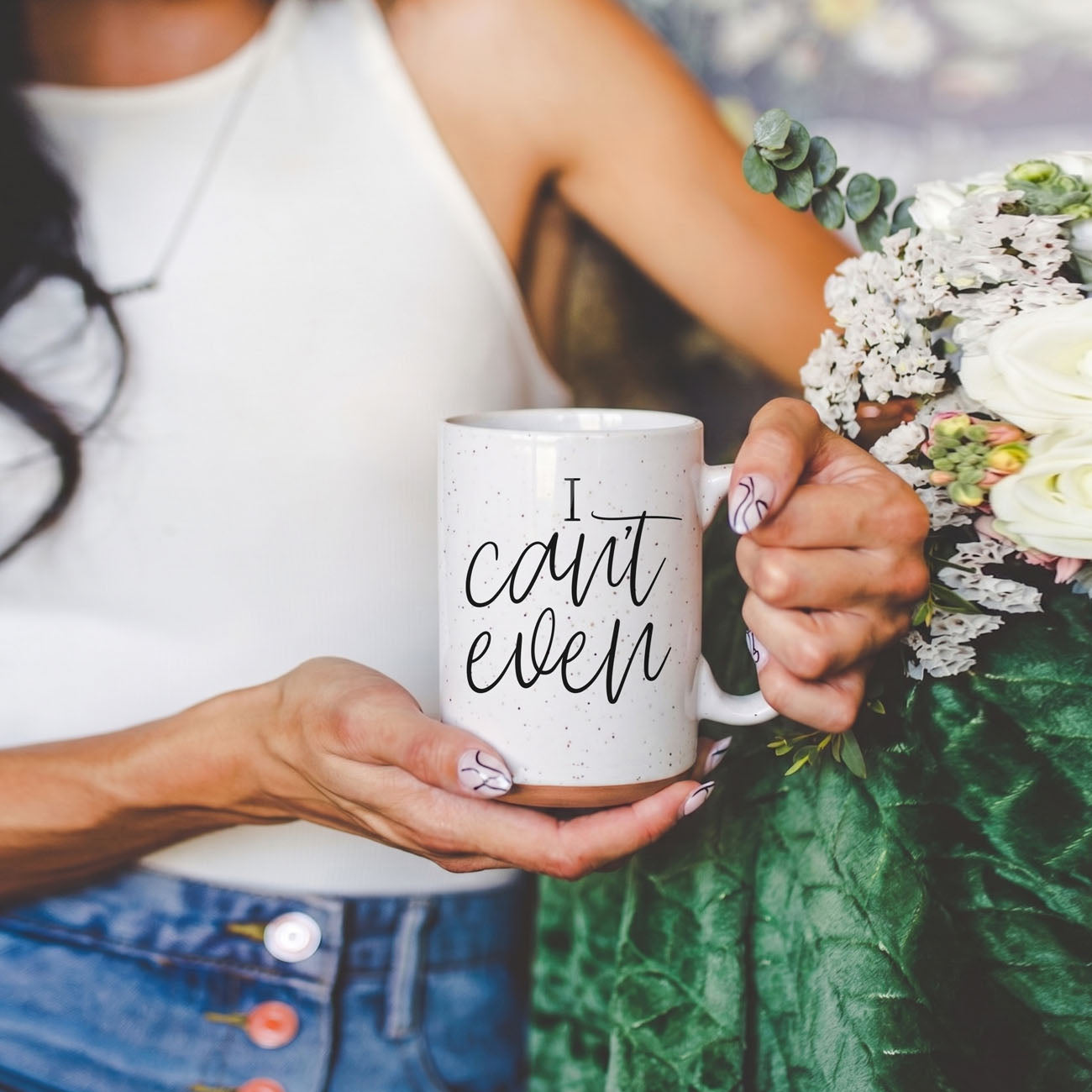 Person holding a mug with 'I can't even' text and a bouquet of flowers.