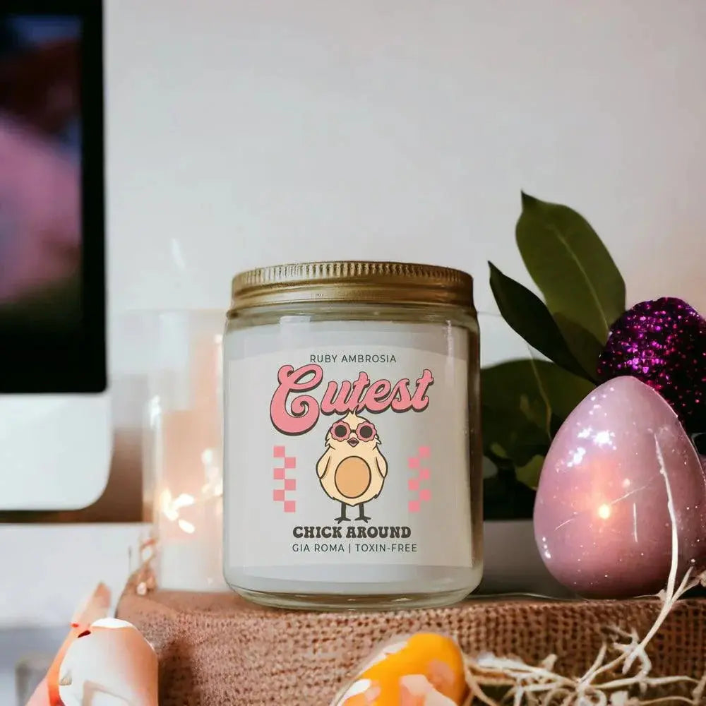 Candle jar with a decorative label featuring a chick illustration on a surface with eggs and plants.