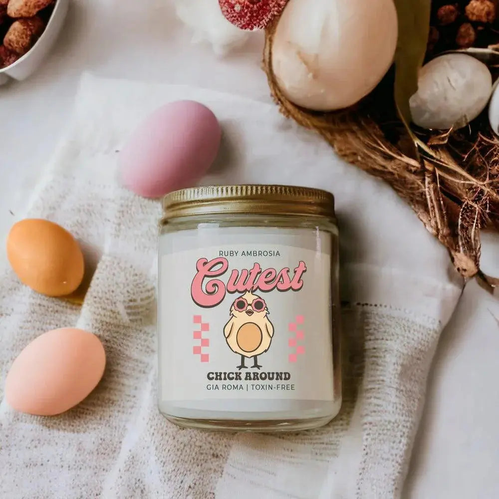 Candle jar labeled 'Cutest Chick Around' with Easter eggs and a basket in the background