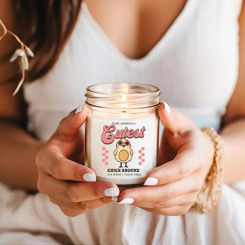 Person holding a lit candle with a 'Cutest Chick Around' label