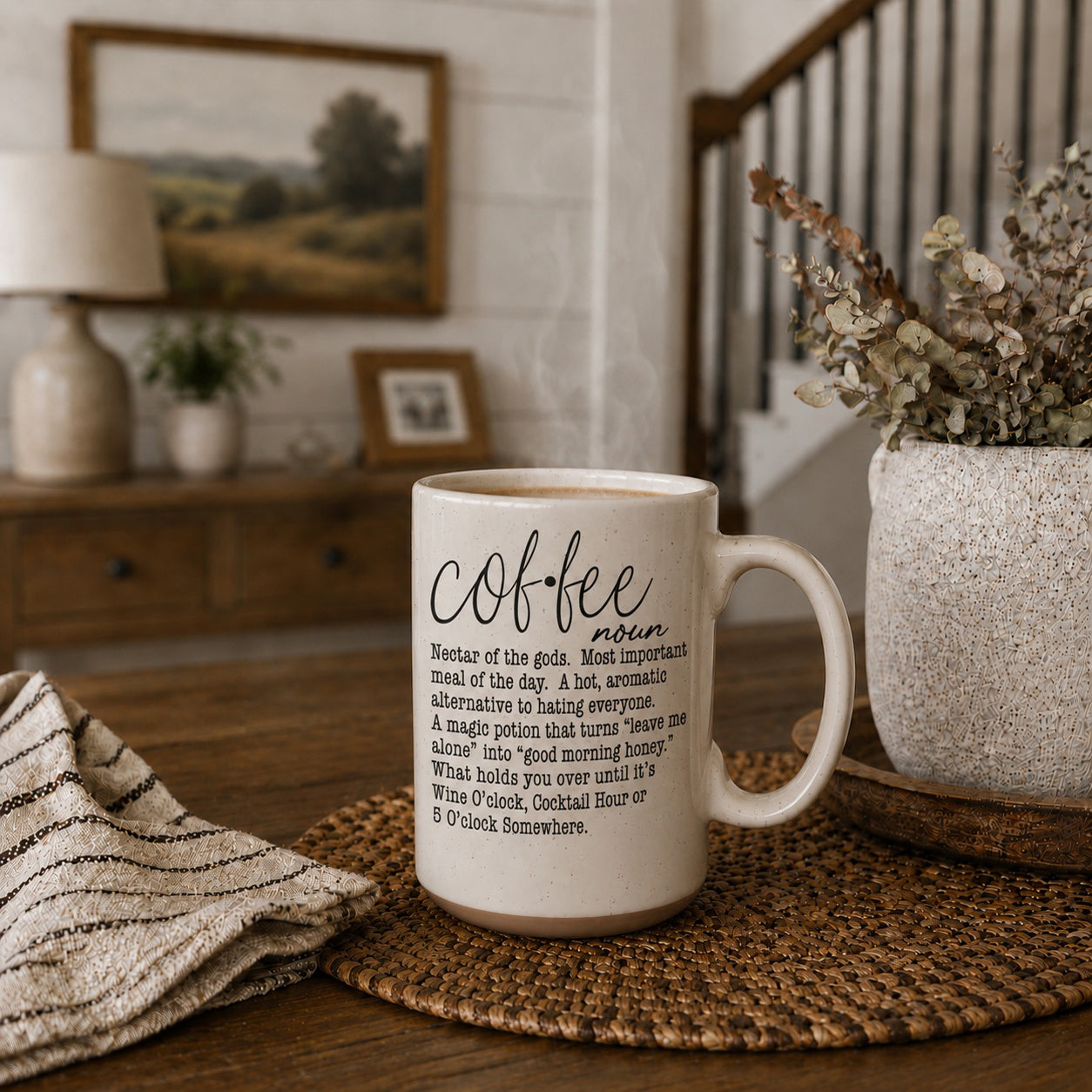 White mug with 'Coffee' definition text on a wooden table with decorative items.