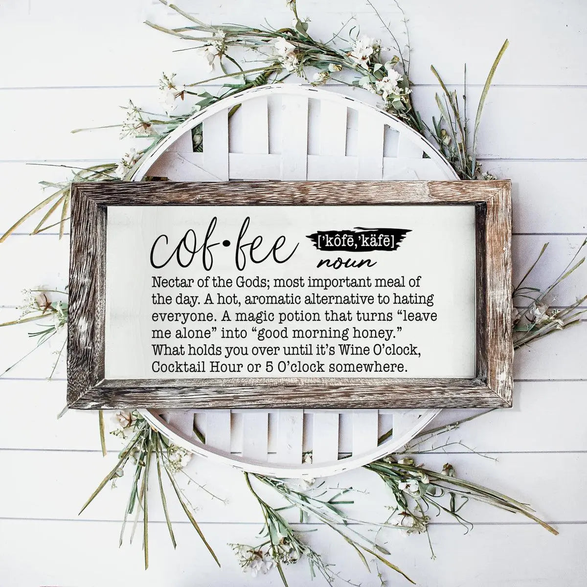 Decorative sign with coffee definition on a white wooden background with greenery