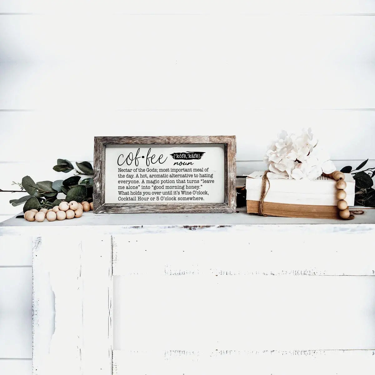 Decorative sign on a white surface with text and decorative items.