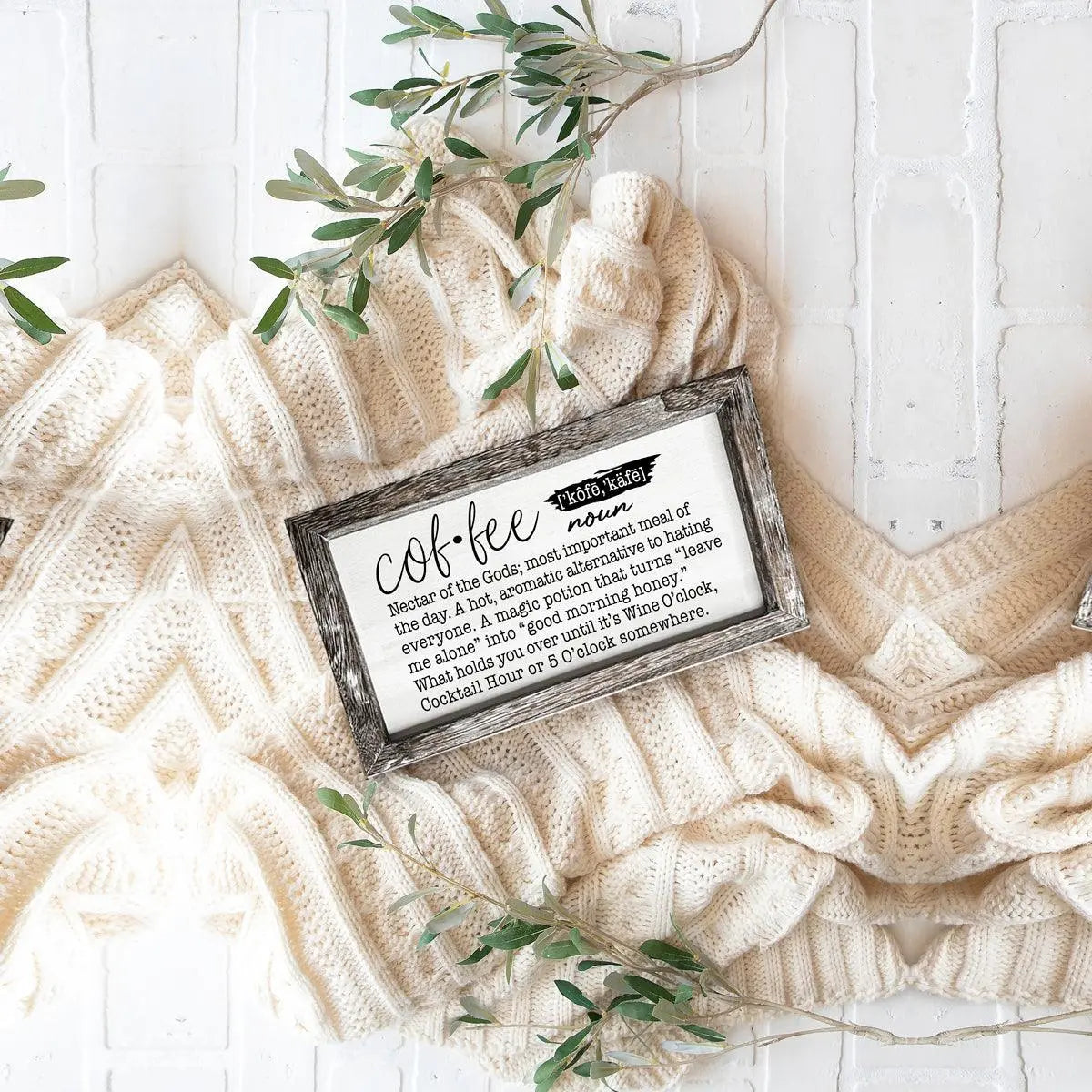 Decorative sign with 'coffee' definition on a textured surface with greenery