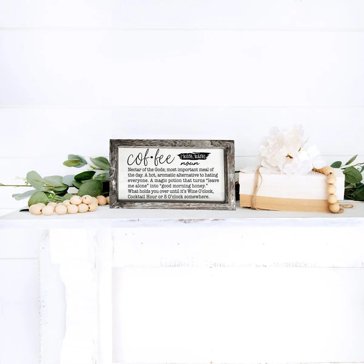 Decorative sign with text on a white surface with greenery