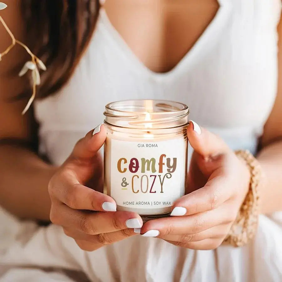 Person holding a 'comfy & cozy' candle jar