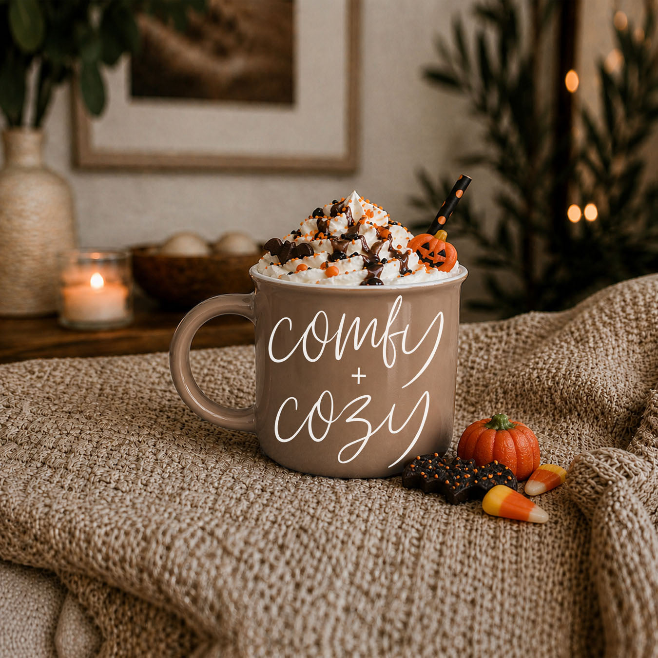 Mug with 'Sweater Weather' text, topped with whipped cream and Halloween decorations, on a textured surface.