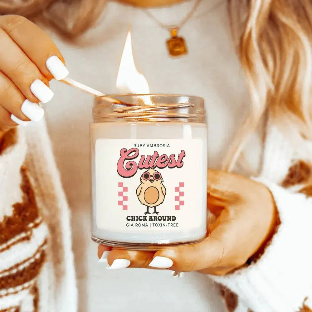 Person holding a lit candle with a 'Cutest Chick Around' label