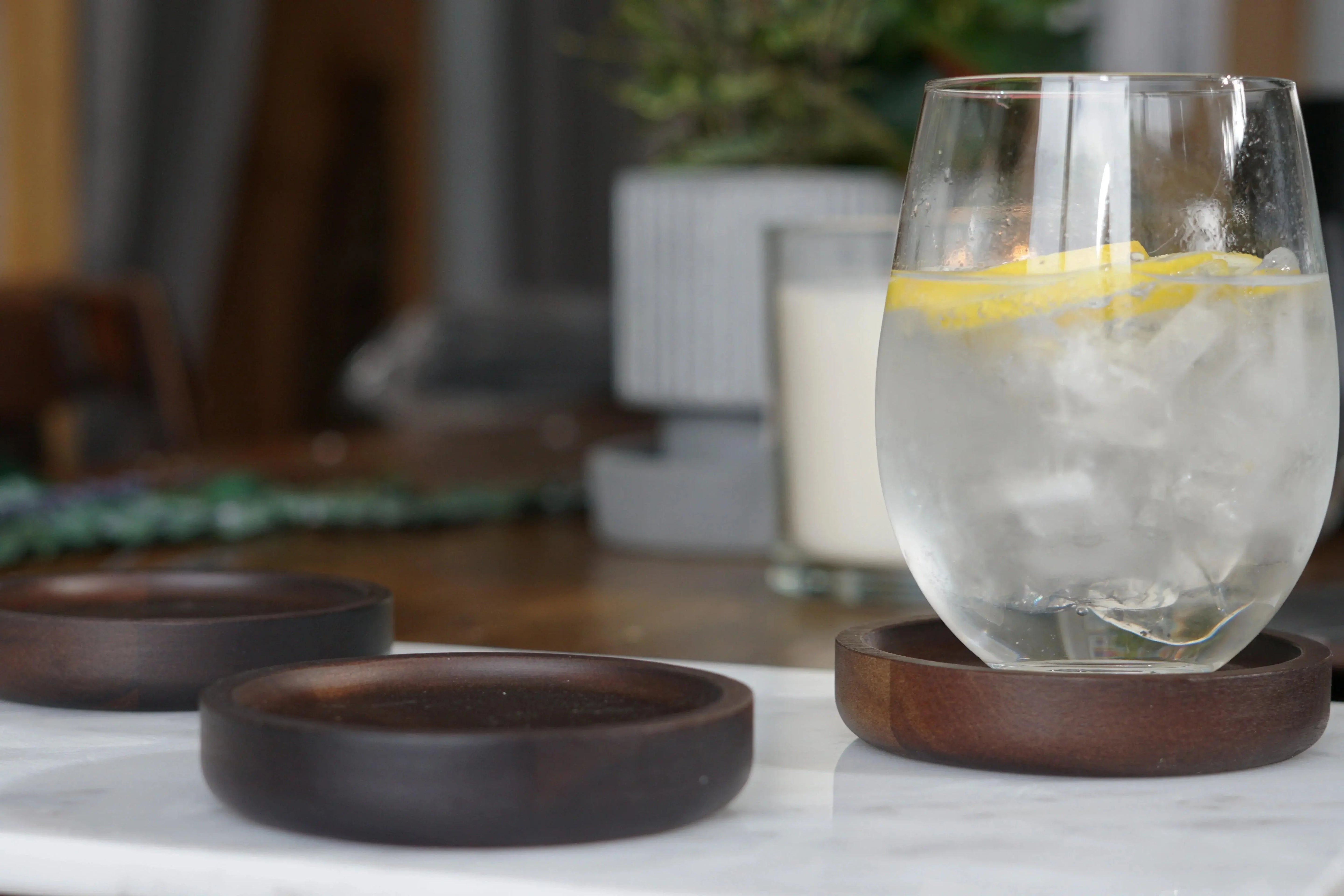 Wooden coasters with lemon water glass, cozy farmhouse table setting