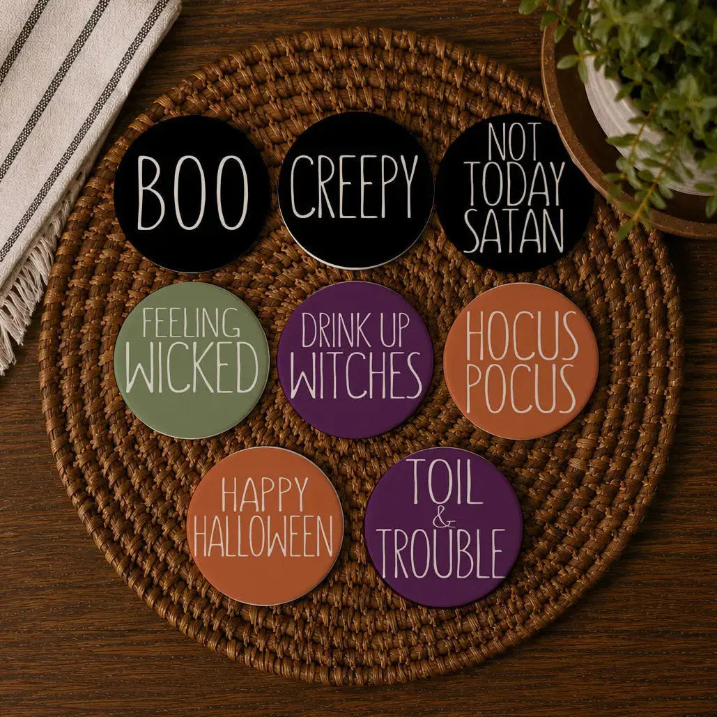 Set of Halloween-themed coasters on a woven mat with a plant and striped fabric in the background.