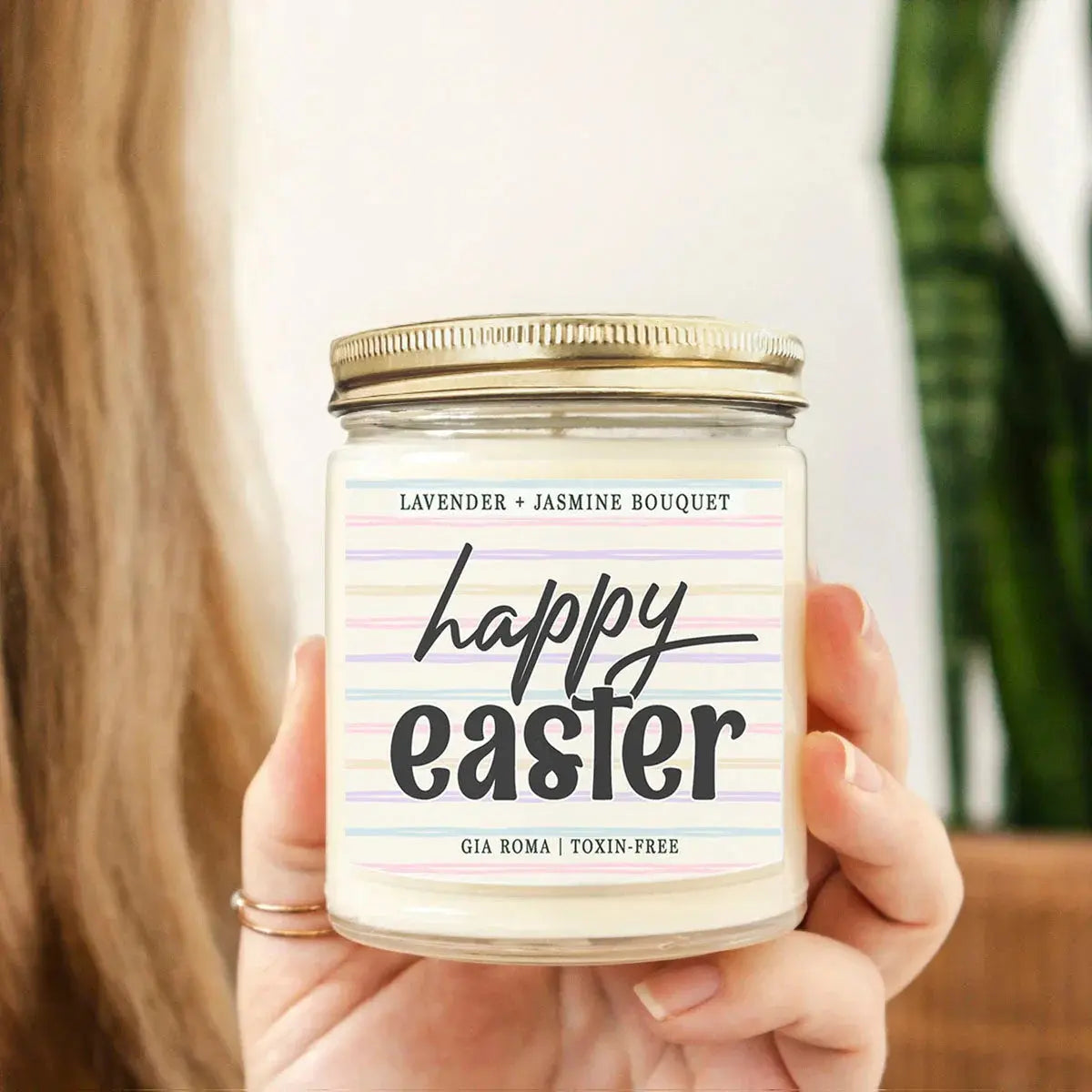 Hand holding a 'Happy Easter' candle with a colorful label.