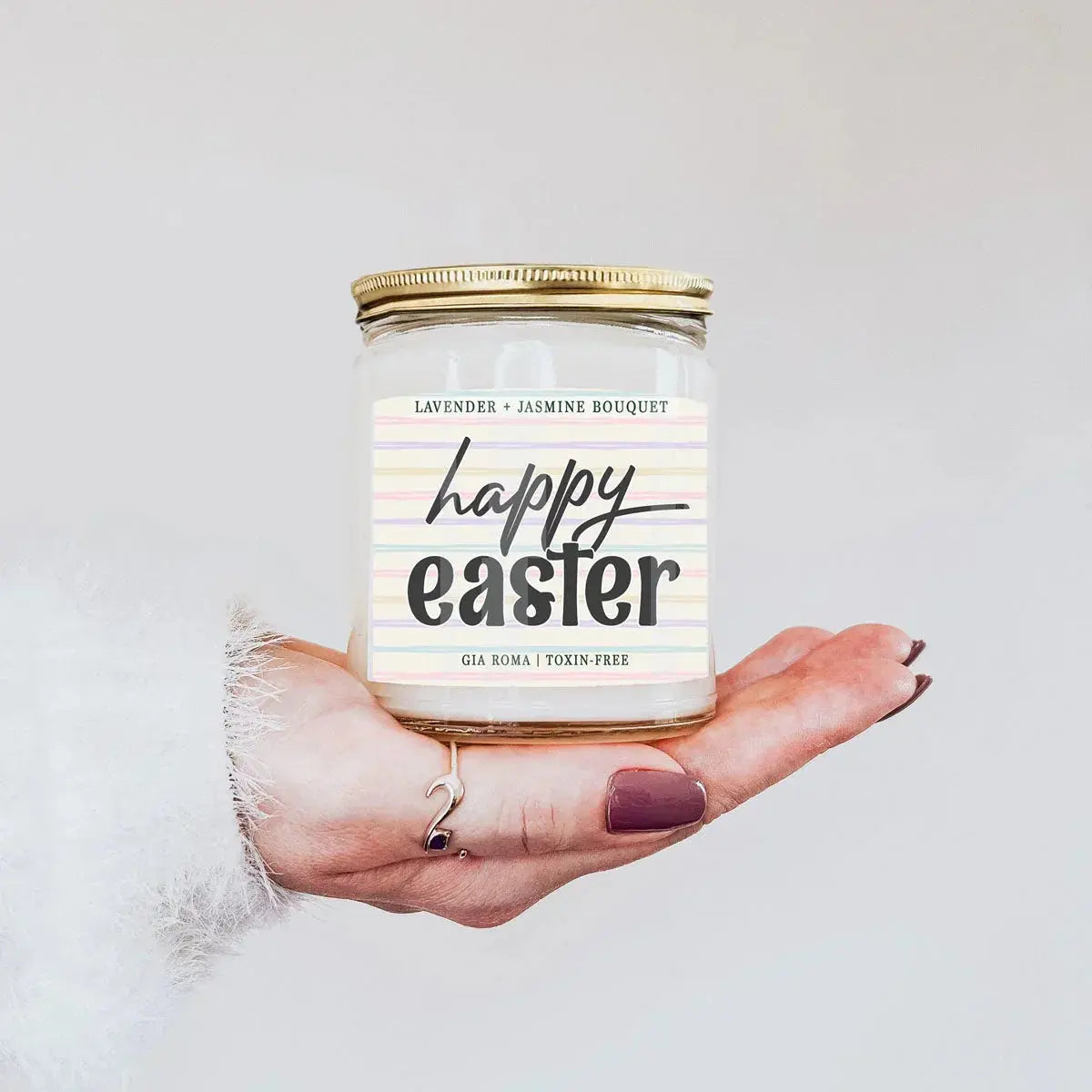 Candle jar labeled 'Happy Easter' held in a hand against a light background