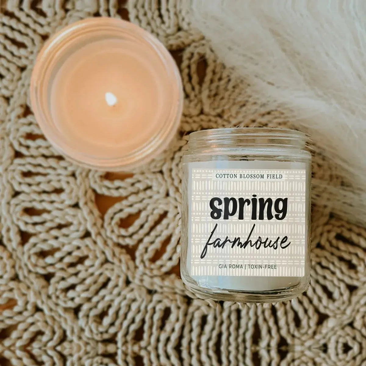 Candle jar labeled 'Spring Farmhouse' on a textured surface