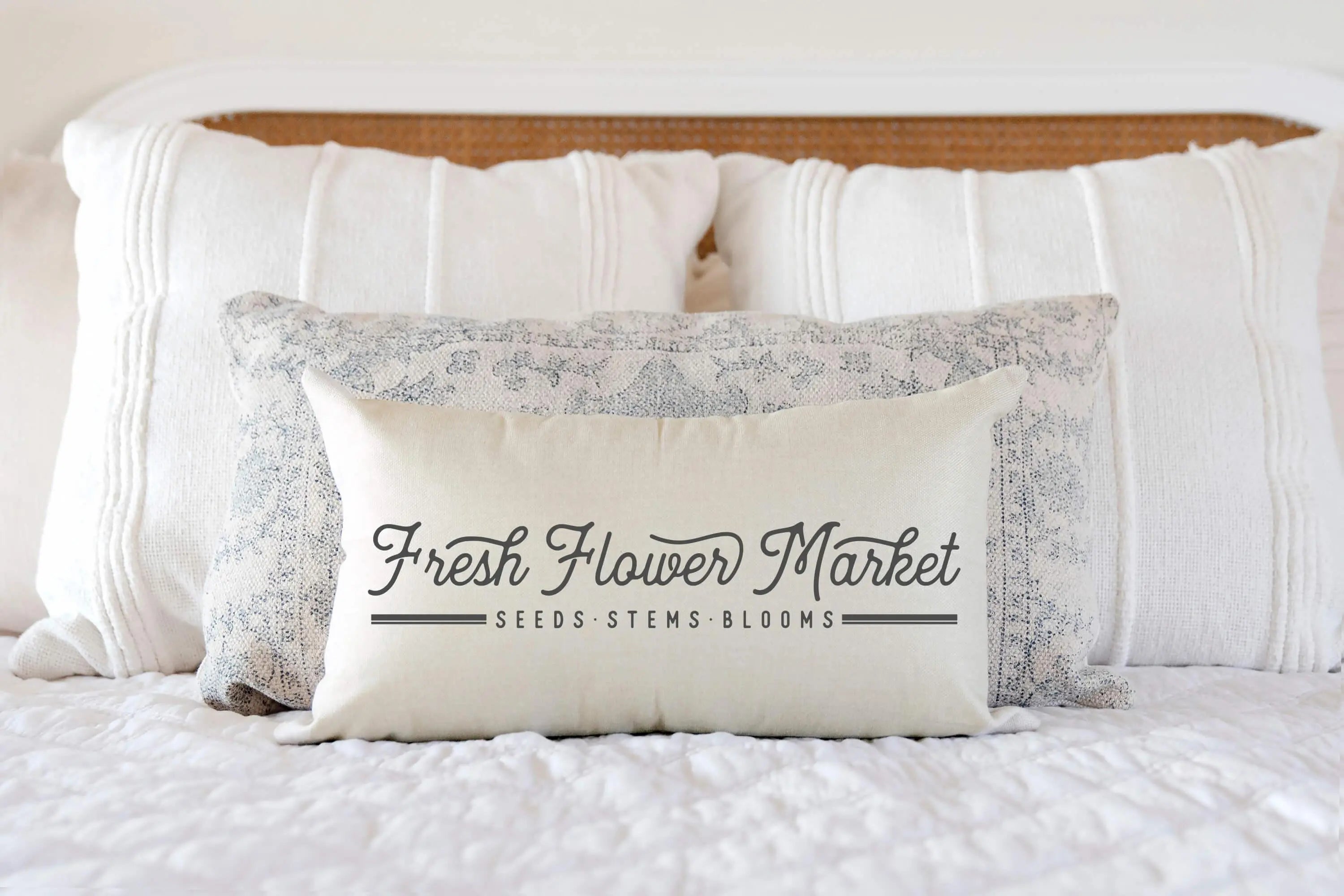 Fresh Flower Market decorative pillow on cozy farmhouse bed with layered white and blue patterned cushions