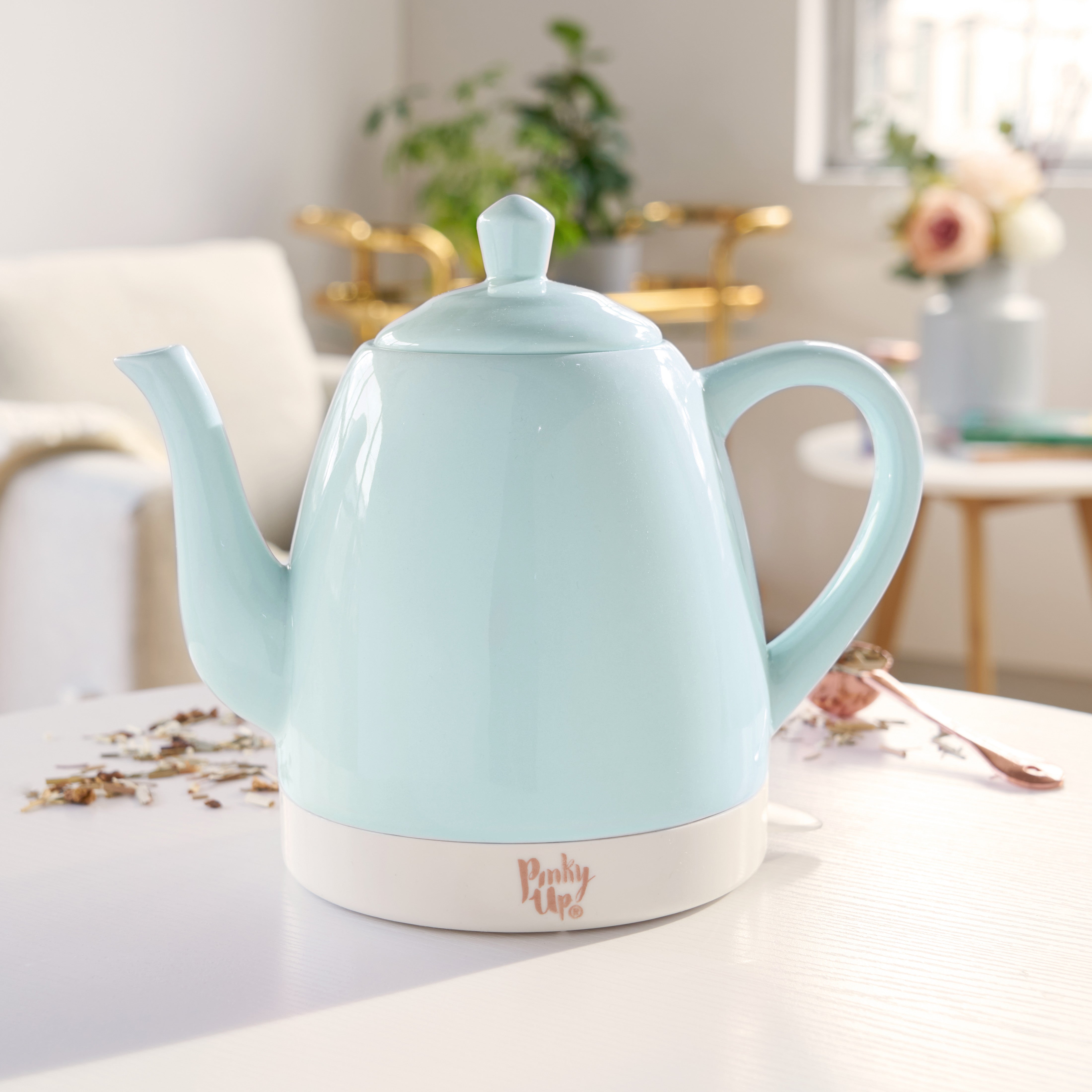 Light blue electric kettle on a white surface with a blurred background