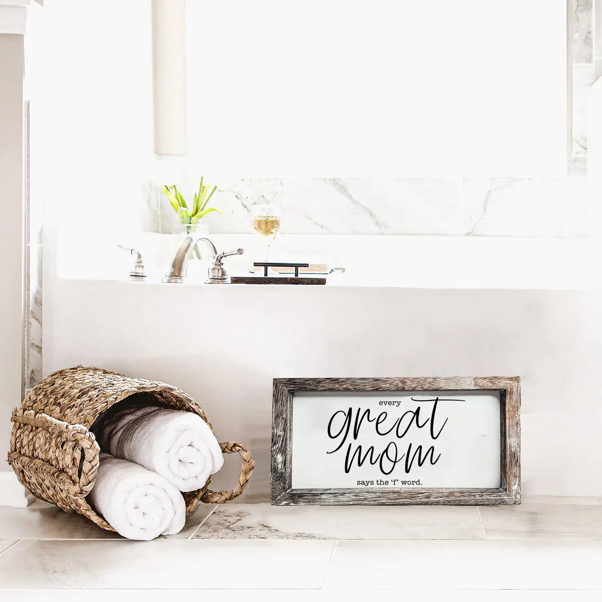 Framed sign with 'Every great mom says the 7th word' text in a bathroom setting.