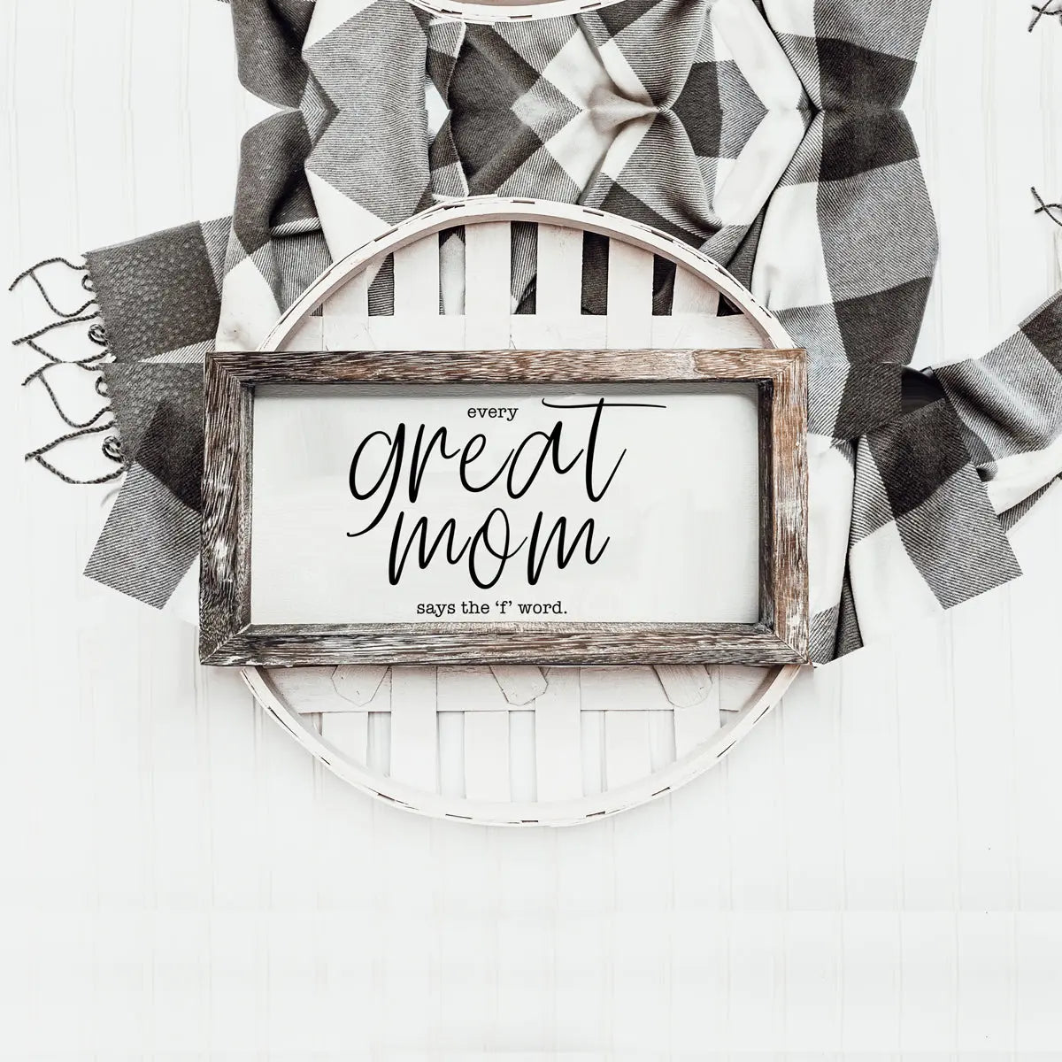 Decorative sign with text on a white background with plaid fabric.