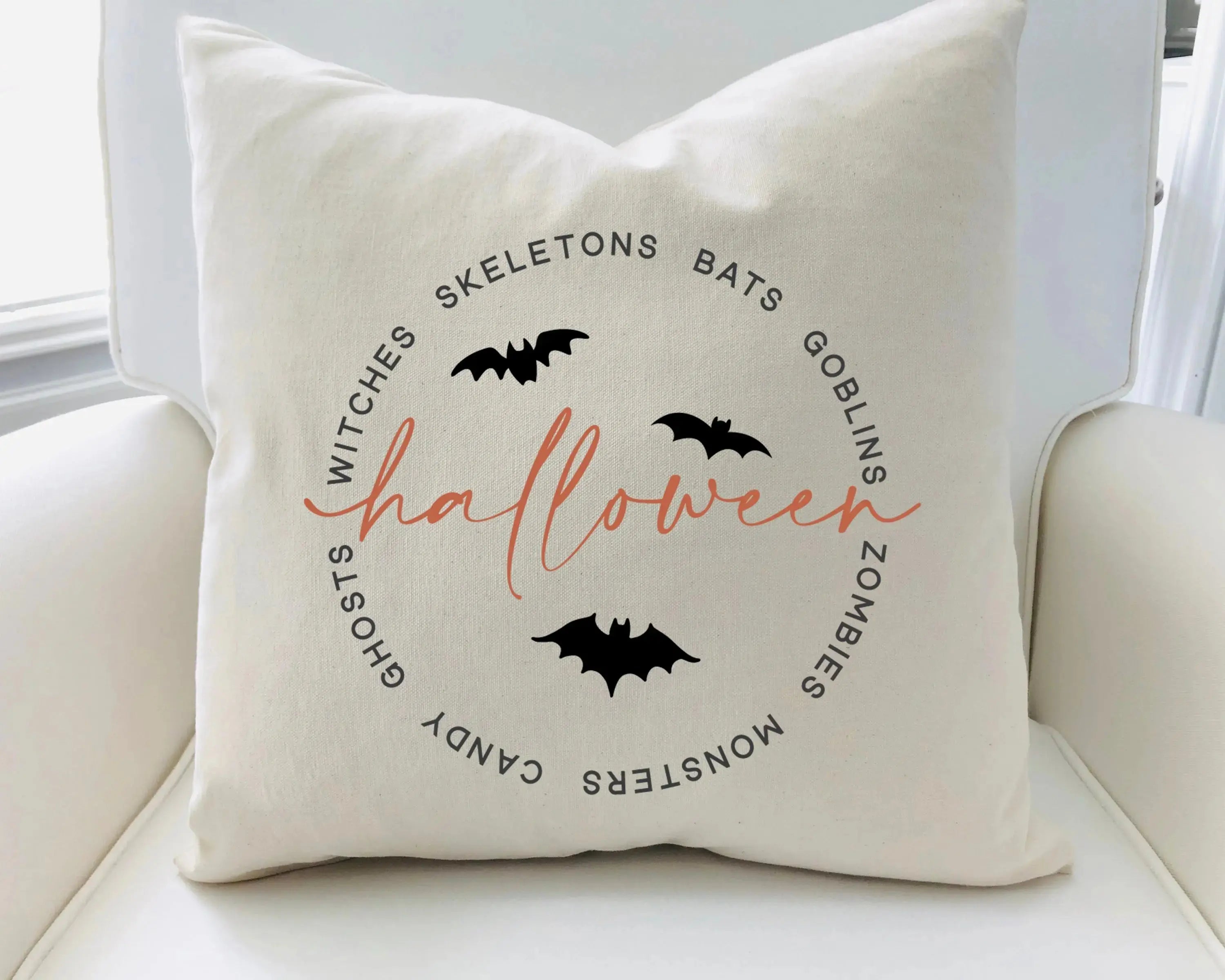 Decorative pillow with Halloween-themed text and bats on a white couch.