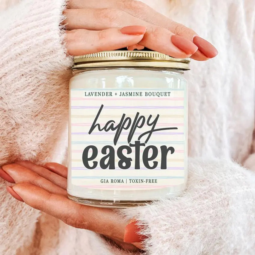 Candle jar labeled 'Happy Easter' held by a person against a soft pink background