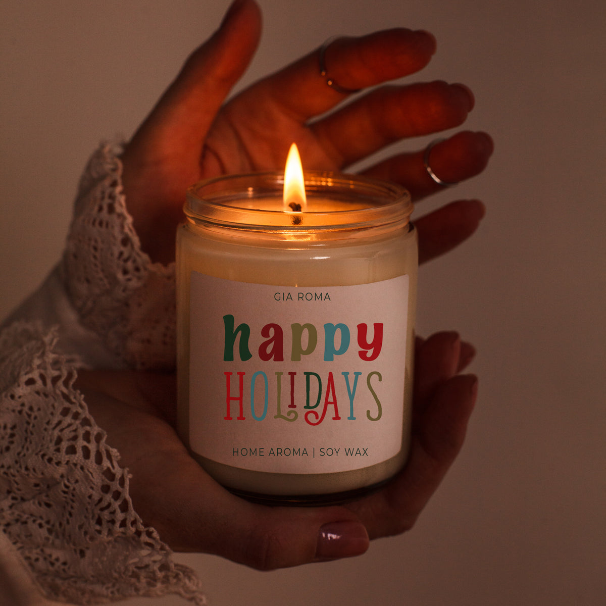 Candle labeled 'happy holidays' held by a hand with a warm glow.