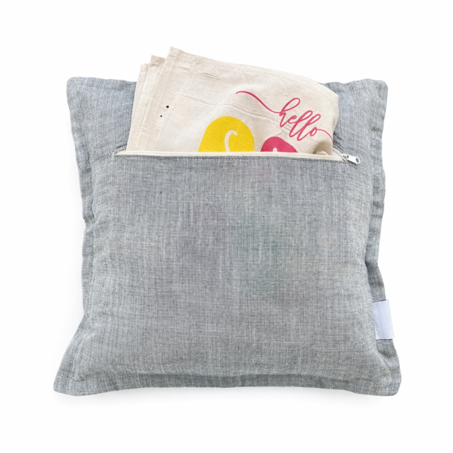Gray pillow with a small pouch on top containing colorful items.