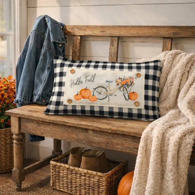 Decorative pillow with 'Hello Fall' text and pumpkins on a wooden bench.
