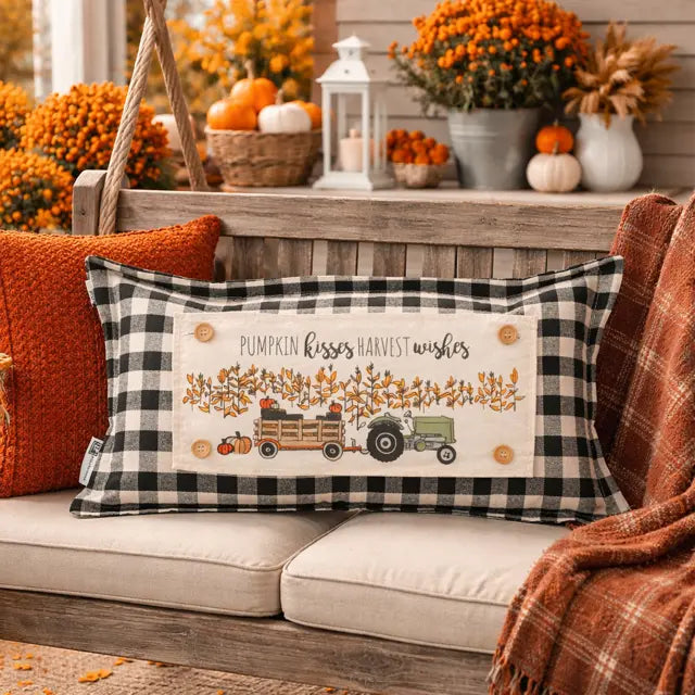 Decorative pillow with autumn design on a couch with fall decorations in the background.