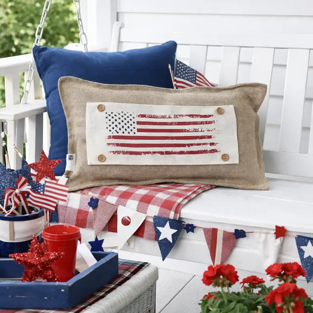 Decorative pillows with American flag design on a white porch swing.