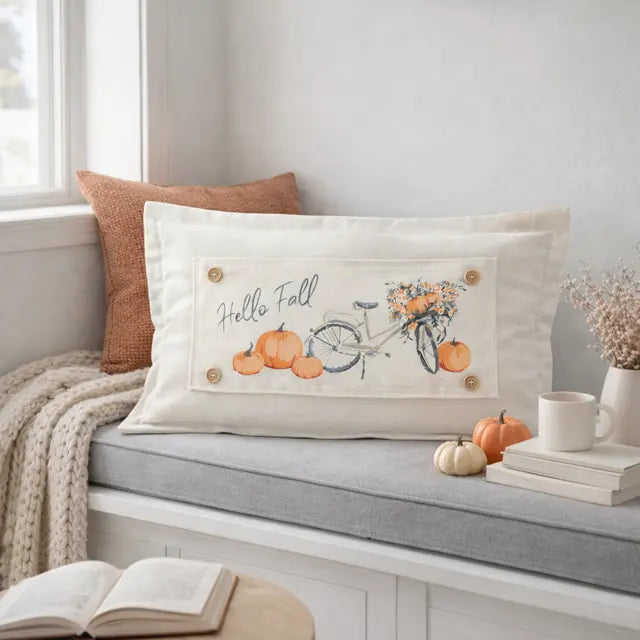 Decorative pillow with 'Hello Fall' text and autumn elements on a bench.